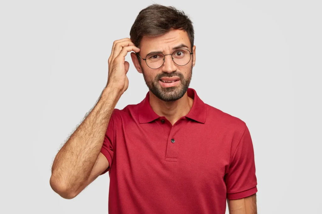 Puzzled young emotional man posing against white wall