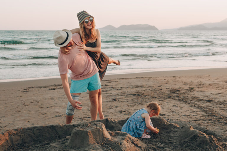 Happy Young Family with Little Kid Having Fun at the Beach. Joyful Family. Travel and Vacation