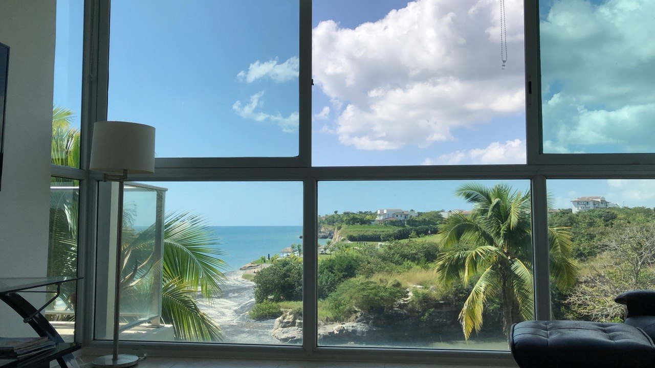 The view from a retirement apartment in Panama looking out at the Pacific Ocean, palm trees and tropical coastline through floor to ceiling windows