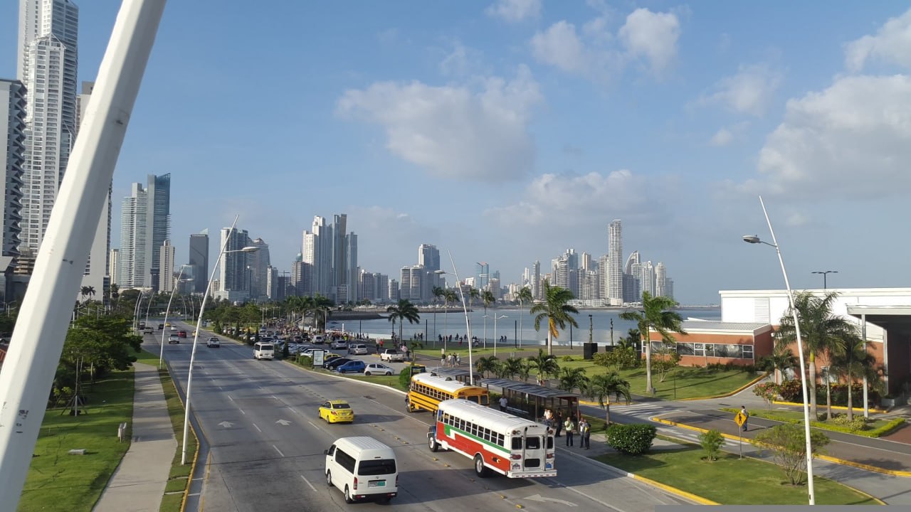 Panama City Cinta Costera skyline with palm trees and a Diablo Rojo bus on the avenue